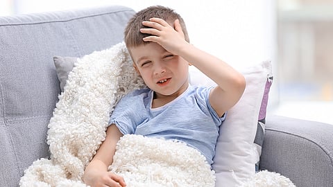 Little boy holidng head, headache, COVID, Long COVID