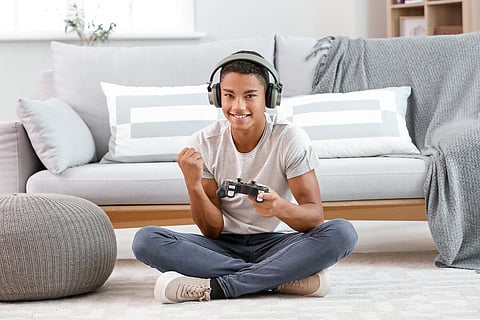 Chico adolescente afroamericano feliz jugando a videojuegos en casa