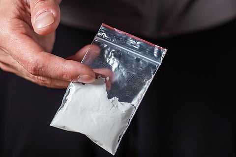 Concept drug addiction. Man hand holds plastic packet or bag with cocaine or another drugs, drug abuse and danger addiction concept.