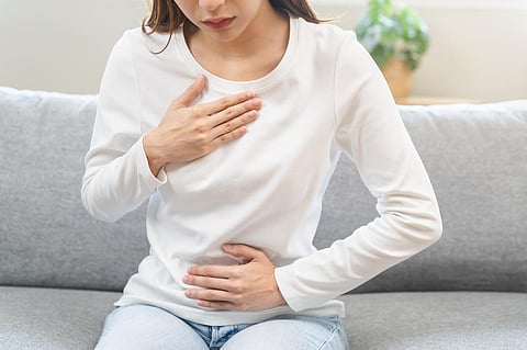 Acid reflux disease, suffer asian young woman have symptom gastroesophageal, esophageal, stomach ache and heartburn pain hand on chest from digestion problem after eat food, Healthcare medical concept