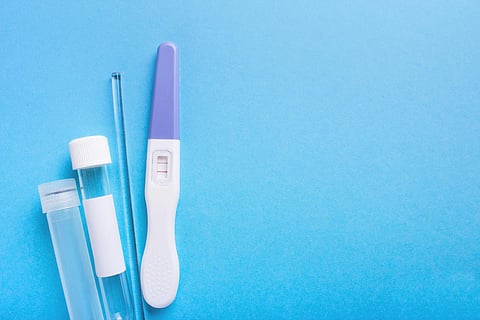 Pregnancy test positive with two stripes and contraceptive pill, test tube. Plastic cover on blue background
