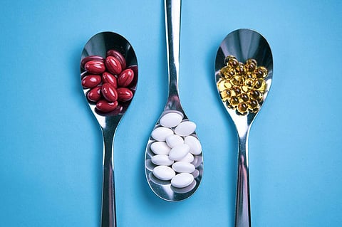 Spoons with pills on a light blue background. Healthy food supplements concept.