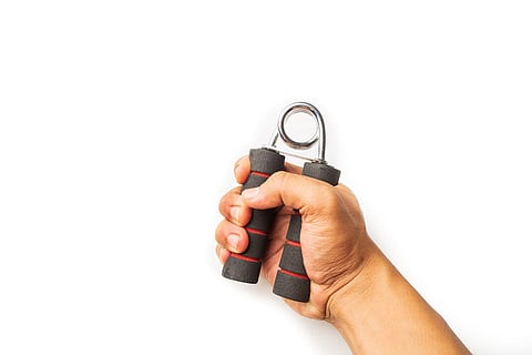 Hand squeezing and gripping hand-grip, strength force, fitness, healthy lifestyle concept on white background, close up selective focus