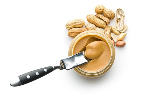 Creamy peanut butter and peanuts  isolated on white background. Spreads peanut butter in the jar.