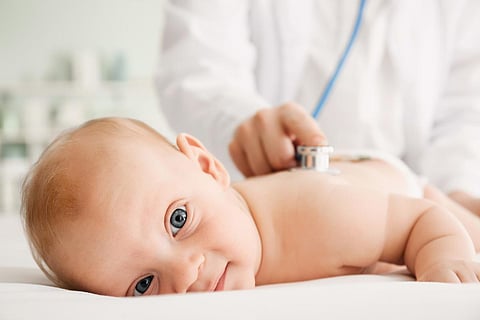 Pediatrician examining cute baby in clinic, closeup