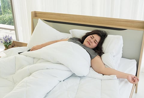 An Asian woman is sleeping in a comfortable bed. 