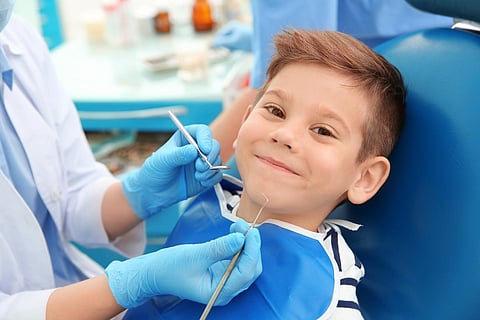 Dentist examining little boy's teeth in clinic