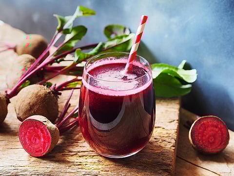 Jugo de remolacha en vaso y remolacha orgánica fresca en mesa de madera rústica para concepto de bebidas refrescantes.