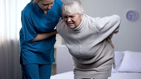 Enfermera que cuida a una anciana que sufre de dolor lumbar, centro médico