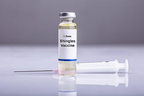Primer plano de la vacuna contra el herpes zóster y la jeringa en el escritorio reflectante