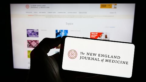Stuttgart, Germany - 07-09-2023: Person holding cellphone with logo of The New England Journal of Medicine (NEJM) on screen in front of webpage. Focus on phone display.
