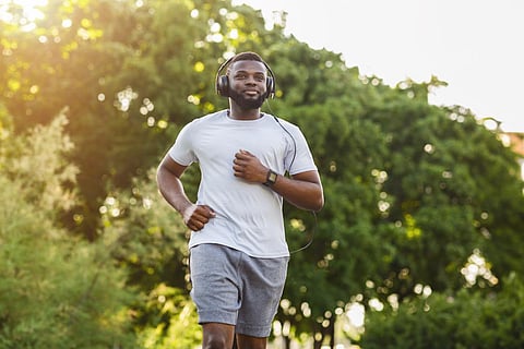 Black Handsome Athlete Running In The Park In Sun Flare, copy space