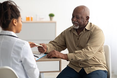 Doctor giving elderly male patient pills, man holding tablets
