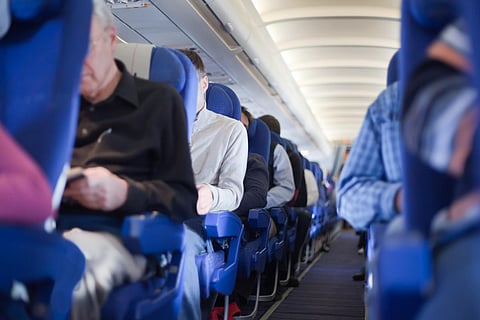 Aisle between the seats in the airplane cabin, shallow depth of focus. People out of focus.