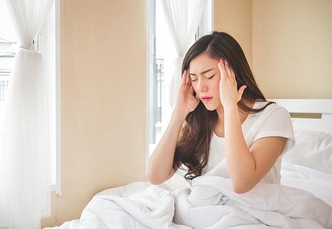 Joven hermosa mujer asiática dolor de cabeza en cama blanca, triste, migraña estresada, llorando, sentimiento decepcionado por la mañana