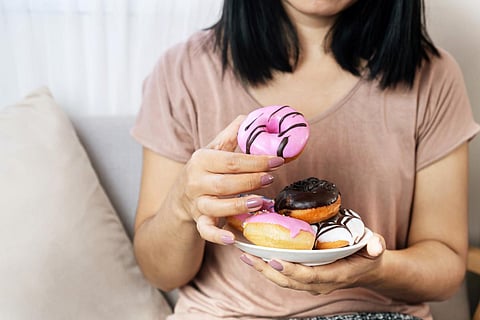 woman hand eating donuts , sugar addiction concept , unhealthy eating sweet food
