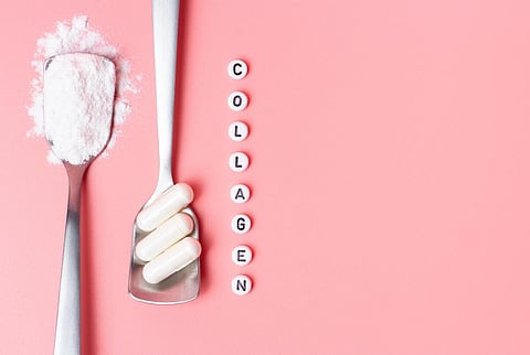 The inscription collagen and capsules with collagen powder on a pink background top view.