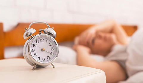 Insomnia problem. Senior woman lying in bed, woke up at 4 am, focus on alarm clock, panorama