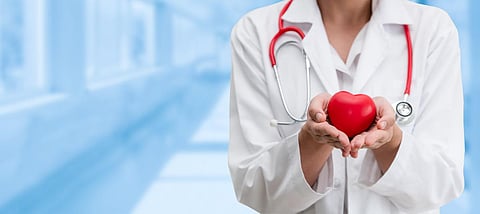 Doctor holding a red heart at hospital office. Medical health care and doctor staff service concept.