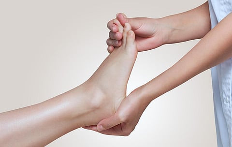 The doctor-podiatrist does an examination and massage of the patient's foot in the clinic.