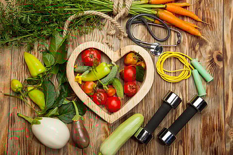 Sport and diet. Healthy lifestyle. Vegetables, dumbbells. Peppers, tomatoes, garlic, onion radish in a heart on white background