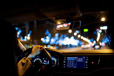 A woman driving a car at night by city