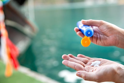 Closeup of a young asian woman applying sunscreen with blur Long-tail boat background. Vacation and travel items