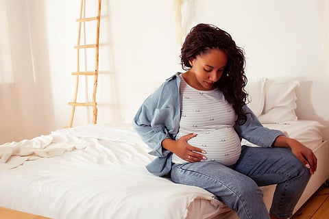 young pretty african american woman pregnant laying in bed, lifestyle people concept close up