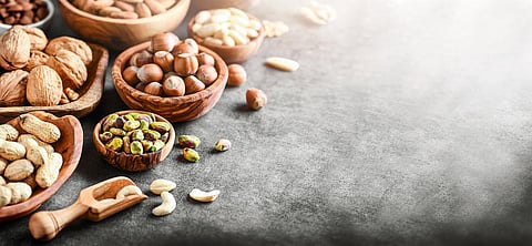 A variety of nuts in wooden bowls from top view copy space. Walnuts, cashew, almond, pistachio, pecan, hazelnut, macadamia and peanut mix selection. Healthy fitness super food banner or panorama.
