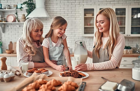 Daughter, mother and grandmother cooking on kitchen. Women generation baking together.