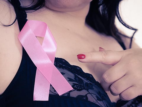 Woman wih pink ribbon on chest. Plus size mature female wearing black bra lingerie showing symbol representing awareness, hope and moral support for breast cancer patients.