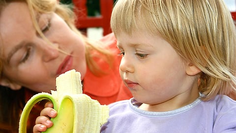Mother and toddler eating banana