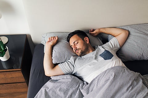 man sleeping on his back in bed