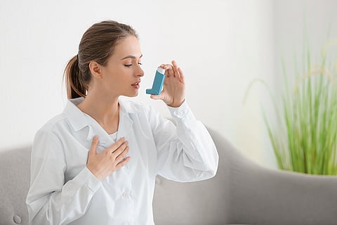 woman using asthma inhaler