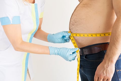 Nurse measuring waist of overweight male