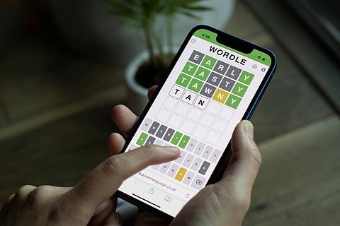 A woman plays Wordle on its official website on her iPhone.