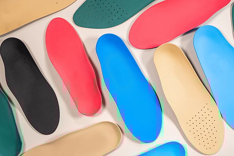 Orthopedic insoles are lined up on a wooden surface. samples of different orthopedic insoles. insoles with a variety of coating.