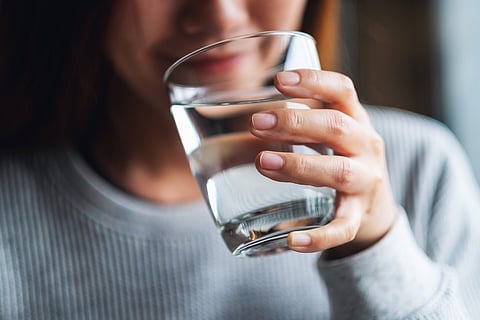 Closeup image of a beautiful young woman holding a glass of water to drink