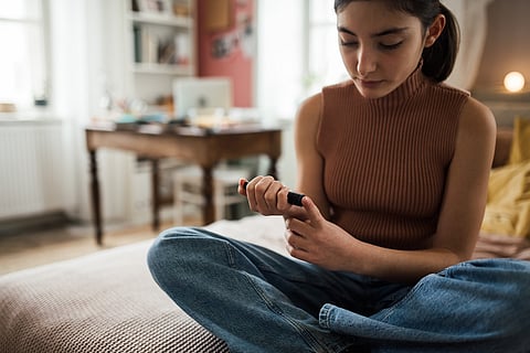 Teenage girl applicating insulin with insulin pen.
