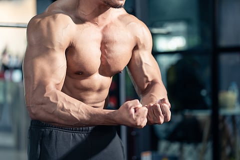 Primer plano de un atleta de culturismo masculino asiático flexionando su músculo.