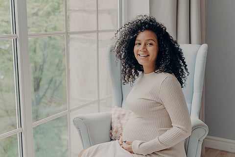 Happy woman in white dress enjoying pregnancy