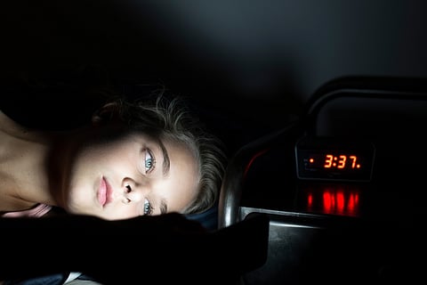 Niña que usa el teléfono móvil en la cama a medianoche, no puede dormir