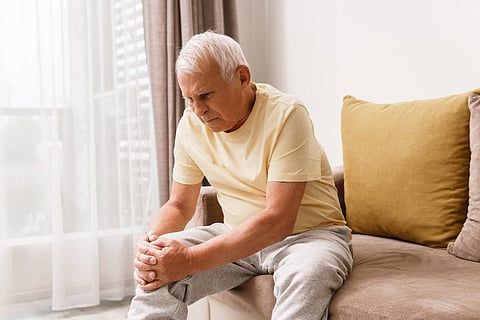Senior man suffering from pain in his knee at home