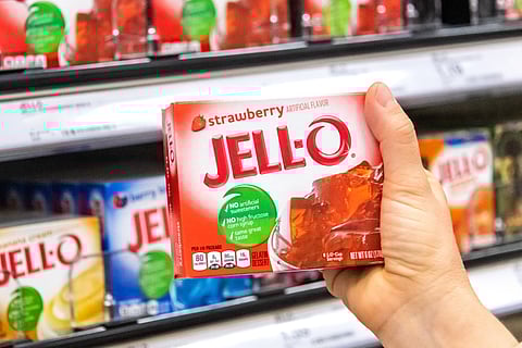 Compradores sosteniendo de la mano una caja de postre de gelatina de fresa y gelatina de gelatina en el pasillo de un supermercado