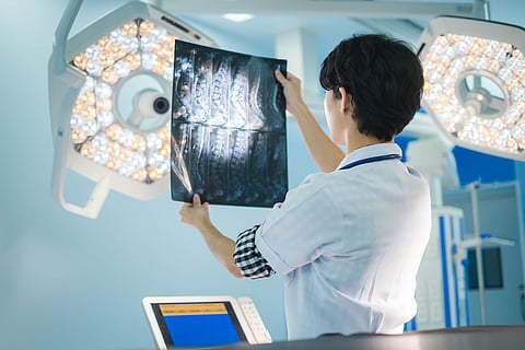 Surgical doctor looking at radiological spinal x-ray film for medical diagnosis on patient’s health on spine disease