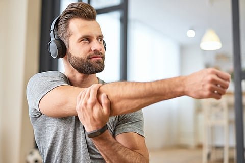 Bearded young man listening to music and stretching hands