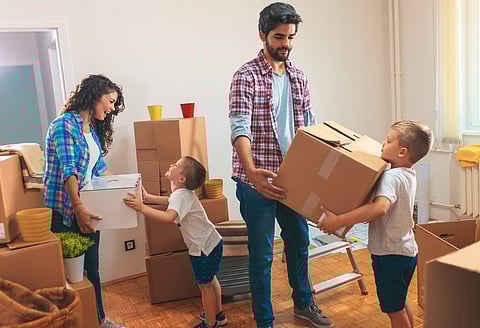 Happy young family moving into their new home. They carrying boxes into the apartment.