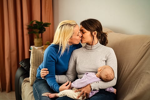 Happy lesbian couple having tender moments with their small baby at home - Family and materhood concept