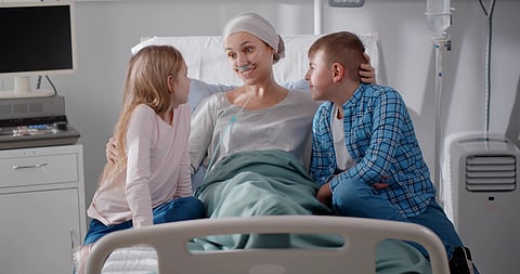 Niños que visitan a la madre tumbada en la cama del hospital tras la quimioterapia
