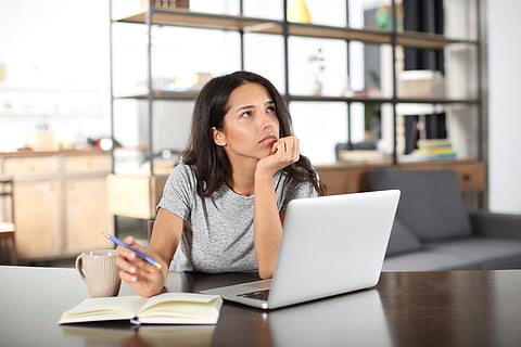Thoughtful young woman working with laptop at home